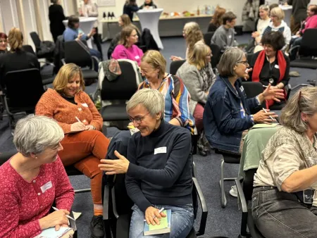 Frauen arbeiten in Kleingruppen im Raum verteilt.