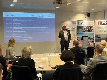 Dr. Martin Makait steht vor dem Publikum, hinter ihm die Leinwand mit der Agenda, vor ihm das Publikum