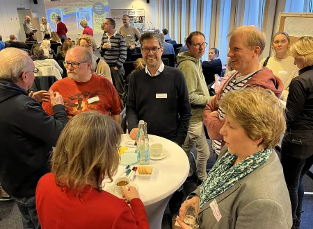 Teilnehmende an Stehtischen und in kleinen Gruppen tauschen sich aus. 